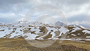 Beautiful mountain landscape. Snow-capped mountains, green hills, blue sky and white clouds