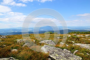 Beautiful mountain landscape with tall grass and stones on a background of blue sky and clouds