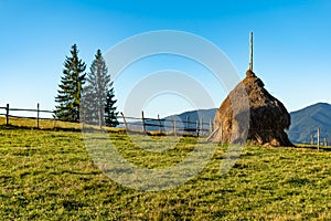 Beautiful mountain landscape with traditional piles of hay on meadow in Romania