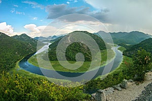 Beautiful mountain landscape with winding river, green forest, thunderstorm and cumulus clouds, top view, Montenegro