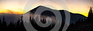 Beautiful mountain panorama of landscape with hazy peaks and foggy wooded valley at sunset