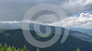 Beautiful mountain panorama with peaks and forest against a cloudy storm sky