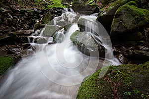 Beautiful mountain rainforest waterfall with fast flowing water and rocks, long exposure.