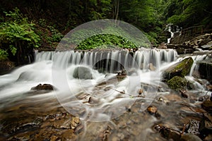 Beautiful mountain rainforest waterfall with fast flowing water and rocks, long exposure.