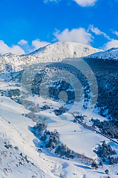 Beautiful mountain range covered in snow with clear sky on sunny day. Ski infrastructure and slopes in Pyrenees, Andorra