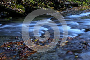 Beautiful mountain river with waterfalls and fallen leaves in a very beautiful mountains valley in autumn season.