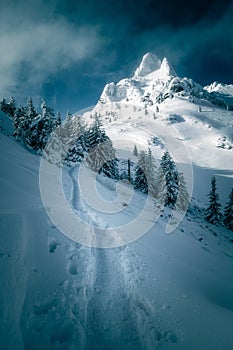 Beautiful mountain scene with a footpath leading to a gigantic mountain peak during winter with massive snow