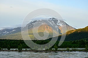 Beautiful mountain with snow patches and flooded river stream