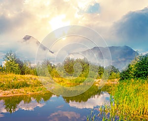 Beautiful mountain valley with small lake and forest at the sunset