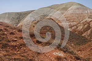 Beautiful mountainous terrain. Steppe landscape with dry grass, red mountains and blue sky. View from a height, panorama.