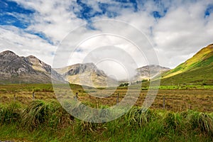 Beautiful mountains in Connemara, county Galway, Ireland; Warm sunny day, Clouds over peaks, Vast green fields