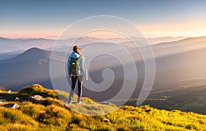 Beautiful mountains in fog and standing young woman with backpack