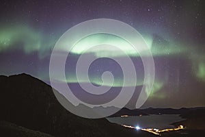 Beautiful mountains near the lake with the background of a breathtaking view of aurora at night