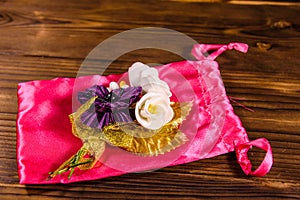 Beautiful multicolored brooch and pink bag on a wooden table