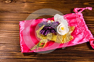 Beautiful multicolored brooch and pink bag on a wooden table