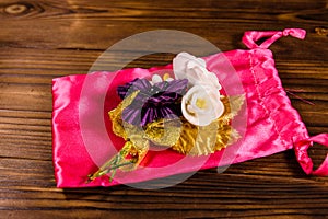 Beautiful multicolored brooch and pink bag on a wooden table