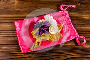 Beautiful multicolored brooch and pink bag on a wooden table