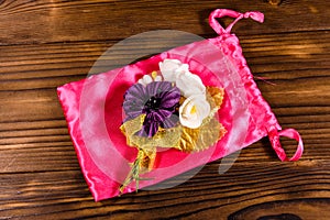 Beautiful multicolored brooch and pink bag on a wooden table. To