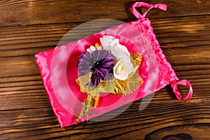 Beautiful multicolored brooch and pink bag on a wooden table. To