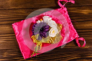 Beautiful multicolored brooch and pink bag on a wooden table. To