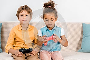 beautiful multiethnic children sitting on couch and playing