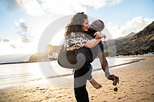 Beautiful multiracial happy young couple laughing, having fun together on the beach. Multi ethnic love concept