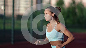 Beautiful muscular fitness woman jumping running intense cardio training at outdoor sportsground
