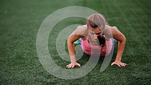 A beautiful muscular girl in pantyhose and a vest makes a burpee at the stadium. Crossfit, fitness, healthy lifestyle