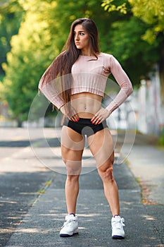 Beautiful muscular girl posing outdoor. athletic woman with big quads