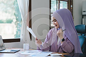 Beautiful muslim business woman wearing a hijab is diligently working at her tablet, displaying professionalism and