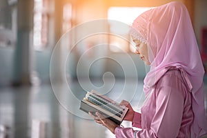 Beautiful Muslim girl reading book with hijab and smiling