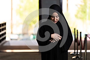 Beautiful Muslim woman in a black dress with hijab praying in a mosque.