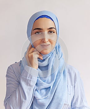 Beautiful Muslim woman in hijab against white background. Portrait of pretty middle-eastern female wearing traditional Islamic