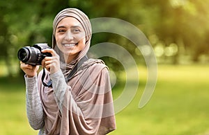 Beautiful muslim woman photographer with digital camera at park