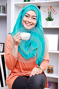 Beautiful muslim woman smiling while holding a cup of tea