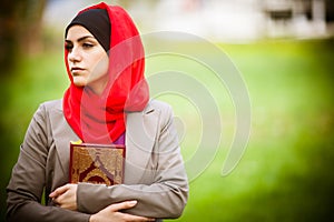 Beautiful muslim woman wearing hijab and holding a holy book Koran.