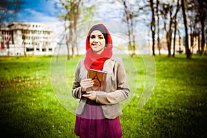 Beautiful muslim woman wearing hijab and holding a holy book Koran.