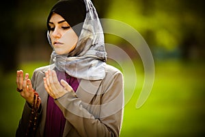 .Beautiful muslim woman wearing hijab praying on rosary / tespih