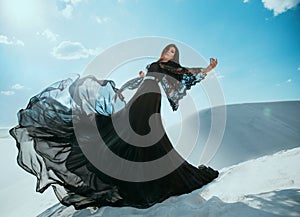 Beautiful mysterious Arab woman queen in black clothes. Girl fashion model posing, dancing in long, silk dress, fabric