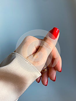 Beautiful nails manicure photo. Red color top nail polish. Female hand, rings, closeup photo, aesthetics. Manicure