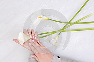 Beautiful nails on woman hands with white calla flowers