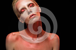 beautiful naked fashionable girl posing with red bodyart and closed eyes