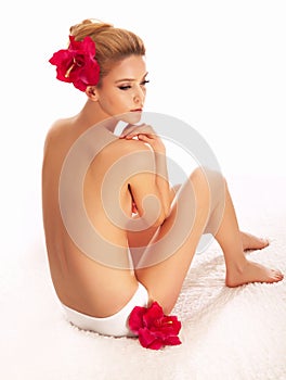 Beautiful naked woman in spa with red flowers.