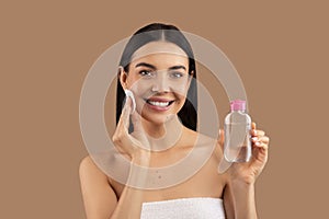 beautiful naked woman using micellar water and cotton pad photo