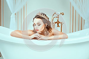 Beautiful naked young woman sitting in expensive jewelry bath.