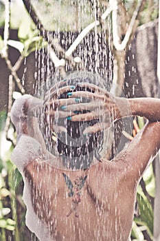 Beautiful naked young woman taking shower in bathroom outside on he luxury villa. Tropical Bali island, Indonesia.