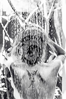 Beautiful naked young woman taking shower in bathroom outside on he luxury villa. Tropical Bali island, Indonesia.