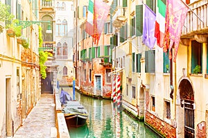 Beautiful narrow canal and street with boats, european union, venice and italian flags in Venice during summer day, Italy.