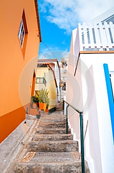 Beautiful narrow cobbled street in Jardim do Mar, Madeira Island, Portugal. Stone staircase along with colorful buildings. Orange