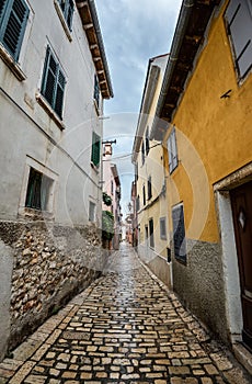 Beautiful narrow street with ancient building facades and paving stones in the coastal town of Rovinj, Croatia